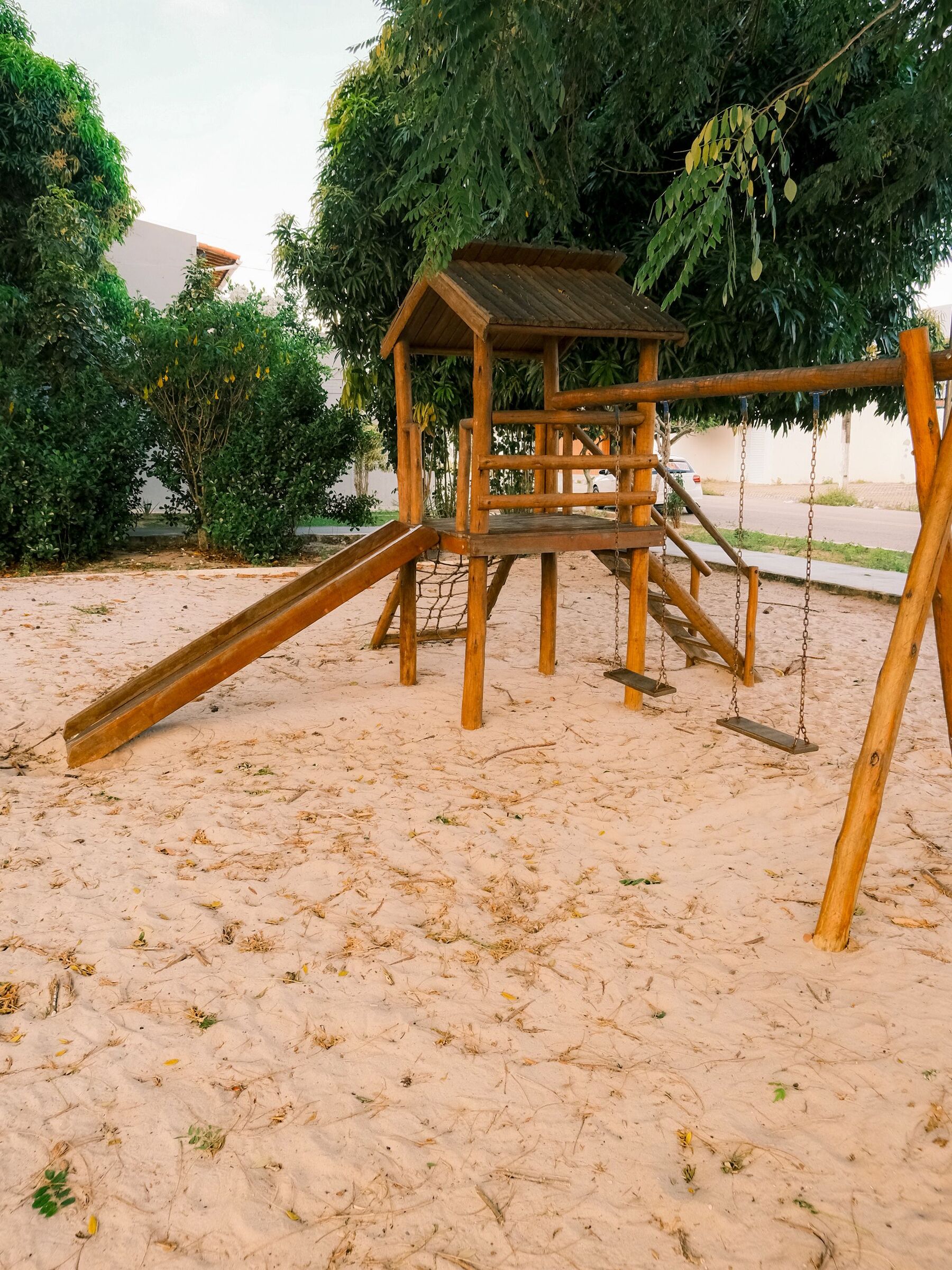 Drewniany plac zabaw na piasku wśród drzew